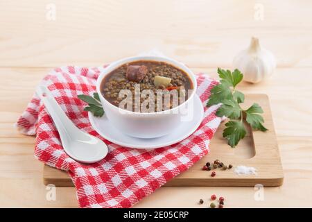 Traditionelles spanisches Gericht aus Linseneintopf mit Chorizo und Kartoffeln, auf einer hellen Holzbasis. Stockfoto