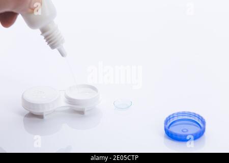 Handauftraglösung in Kontaktlinsengehäuse auf weißem Hintergrund. Stockfoto