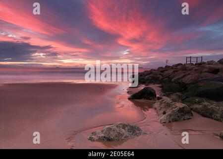 Der wolkige Himmel ist voller magischer, pastellrosa und violetter Farben, wenn die Sonne über dem Meer vor Bournemouth Beach aufgeht. Stockfoto