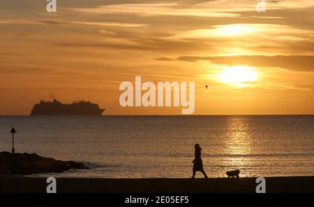 Sandbanks, Großbritannien. Dezember 2020. Hundespaziergänger bei Sonnenaufgang am Strand von Sandbanks in Poole, Dorset. Kredit: Richard Crease/Alamy Live Nachrichten Stockfoto