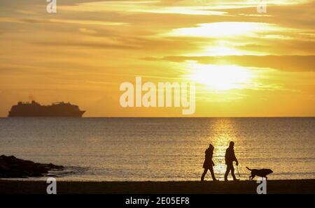 Sandbanks, Großbritannien. Dezember 2020. Hundespaziergänger bei Sonnenaufgang am Strand von Sandbanks in Poole, Dorset. Kredit: Richard Crease/Alamy Live Nachrichten Stockfoto