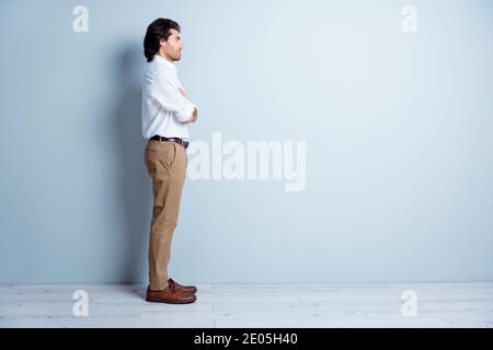 Foto Portrait Ganzseitenansicht von selbstbewussten Mann suchen Bei leerem Raum mit gefalteten Armen isoliert auf klarem Weiß Farbiger Hintergrund Stockfoto