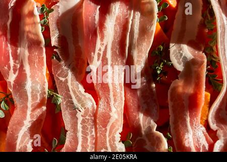 Auf dem Backblech Scheiben leckerer Rohspeck mit Kräutern und Kürbiswürfeln. Nahaufnahme. Draufsicht. Stockfoto