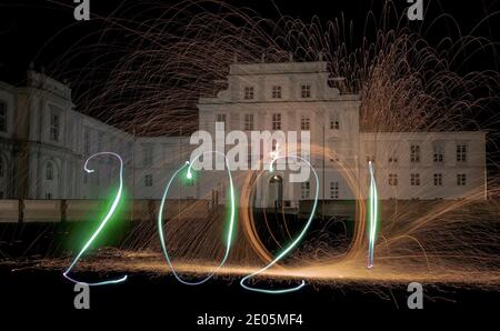 Oranienburg, Deutschland. Dezember 2020. Eine Frau hat das Jahr 2021 mit einer Taschenlampe vor Schloss Oranienburg (Brandenburg) gezeichnet. (Langzeitbelichtung) Kredit: Paul Zinken/dpa/Alamy Live Nachrichten Stockfoto