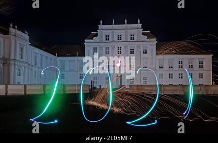 Oranienburg, Deutschland. Dezember 2020. Eine Frau hat das Jahr 2021 mit einer Taschenlampe vor Schloss Oranienburg (Brandenburg) gezeichnet. (Langzeitbelichtung) Kredit: Paul Zinken/dpa/Alamy Live Nachrichten Stockfoto