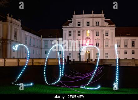 Oranienburg, Deutschland. Dezember 2020. Eine Frau hat das Jahr 2021 mit einer Taschenlampe vor Schloss Oranienburg (Brandenburg) gezeichnet. (Langzeitbelichtung) Kredit: Paul Zinken/dpa/Alamy Live Nachrichten Stockfoto