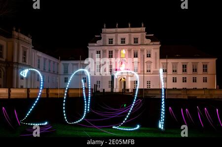 Oranienburg, Deutschland. Dezember 2020. Eine Frau hat das Jahr 2021 mit einer Taschenlampe vor Schloss Oranienburg (Brandenburg) gezeichnet. (Langzeitbelichtung) Kredit: Paul Zinken/dpa/Alamy Live Nachrichten Stockfoto