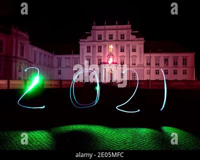 Oranienburg, Deutschland. Dezember 2020. Eine Frau hat das Jahr 2021 mit einer Taschenlampe vor Schloss Oranienburg (Brandenburg) gezeichnet. (Langzeitbelichtung) Kredit: Paul Zinken/dpa/Alamy Live Nachrichten Stockfoto