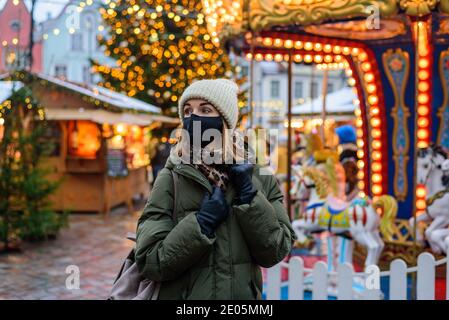 Frau in Gesichtsmaske auf dem Weihnachtsmarkt in Tallinn, Estland Stockfoto