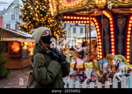 Frau in Gesichtsmaske auf dem Weihnachtsmarkt in Tallinn, Estland Stockfoto