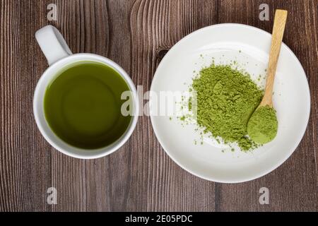 tasse Matcha-Tee und Matcha-Grünteepulver in Schüssel auf Holztisch. Ansicht von oben. Gesundes Lebensmittelkonzept Stockfoto