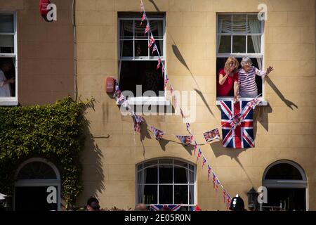 Menschen, die aus einem Fenster hingen, winken den Menschenmassen während der Hochzeit von Prinz Harry und Meghan Markle, die am 19. Mai 2018 im Windsor Castle, Großbritannien, stattfand. Stockfoto