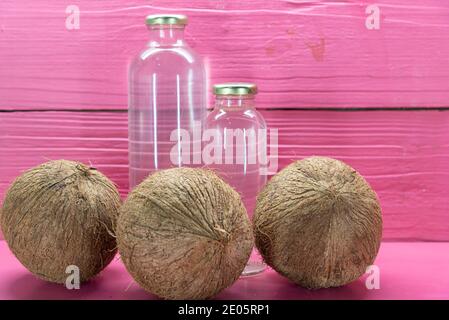 Getrocknete Kokosnüsse. Frisches Obst. Pinkfarbene Flaschen auf Holzhintergrund. Erfrischendes Getränk. Kokoswasser. Energy Drink. Stockfoto