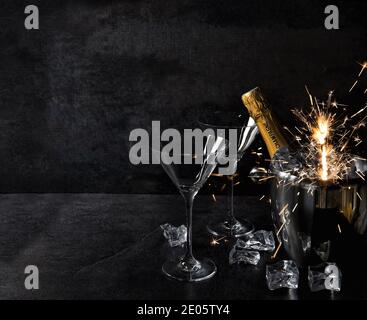 Champagner mit zwei Gläsern. Feiertage Dekoration Wunderkerzen auf dunklem Hintergrund Stockfoto