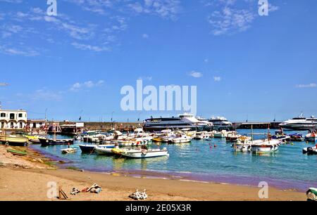 Landschaft mit kleinem Hafen mit Strand und Booten Die Insel und der wolkige blaue Himmel Hintergrund Stockfoto