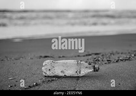 Schwarz-Weiß-Ansicht des Plastikflaschenabfalls auf dem Band Meeresküsten-Ökosystem, Konzept der Umweltverschmutzung Stockfoto