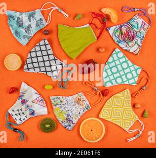 Stoff Gesichtsmaske mit Baumwolle Stoff Blumenmuster handgefertigten Kunsthandwerk. Niedliche Masken mit bunten Obstsorten auf orangefarbenem Hintergrund. Gesunde Lebenshaltung Stockfoto