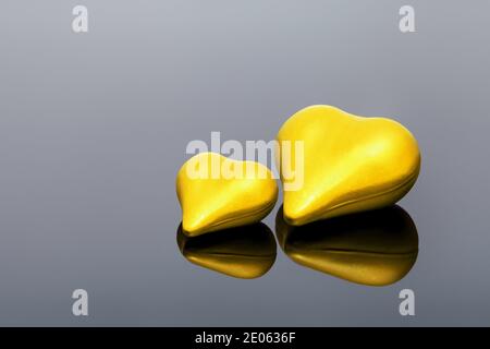 Gelbe volumetrische Paar Herzen das Symbol der Liebe liegt auf schwarzem Glas mit Reflexion, einsame Herzen valentines Tag Hintergrund mit Copy Space, nobod Stockfoto