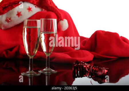 Feier der Weihnachtsfeiertage mit zwei Gläsern Champagner, einem Band und einem roten Weihnachtsmann Kostüm im Hintergrund Stockfoto