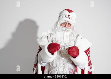 Vater Frost in langen warmen Mantel, rote Fäustlinge und ein Hut hält Geld in den Händen Stockfoto