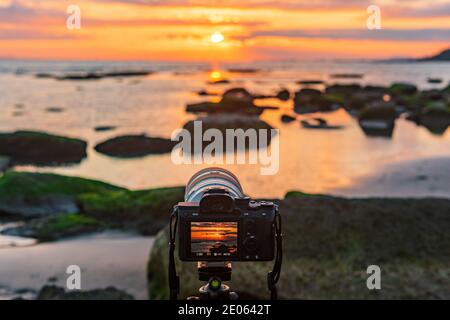 Kamera auf Stativ fängt den farbenfrohen Sonnenaufgang ein Stockfoto