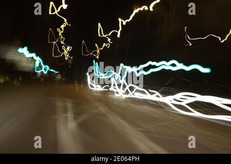 Der Fahrer sieht durch die Windschutzscheibe Scheinwerfer, verzerrte, verschwommene Sicht durch Drogen- oder Alkoholvergiftung bei Nachtfahrten Stockfoto