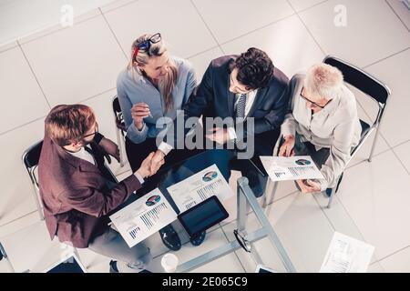 Ansicht von oben. Kollegen aus der Wirtschaft schütteln sich im Einvernehmen die Hände. Stockfoto