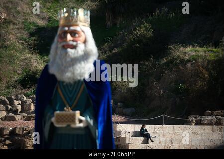 Malaga, Spanien. Dezember 2020. Eine Frau mit Gesichtsmaske sitzt hinter einer riesigen Figur, die Gaspar darstellt, einer der drei Weisen in der Alcazabilla Straße.das Rathaus von Málaga hat in Straßen und Plätzen riesige Figuren der drei Weisen platziert, die Kinder und Familien genießen und besuchen können. Ein paar Tage vor der Epiphanie Parade der drei Könige. Die Zahlen messen 5 Meter und sind mit Schutzschirmen isoliert, um die Coronavirus-Krankheit zu verhindern. Kredit: SOPA Images Limited/Alamy Live Nachrichten Stockfoto