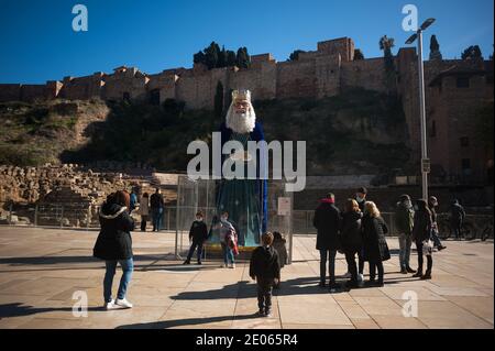 Malaga, Spanien. Dezember 2020. Man sieht eine Frau, die ein Foto macht, während Kinder vor einer riesigen Figur posieren, die Gaspar, einen der drei Weisen, in der Alcazabilla Straße darstellt.das Rathaus von Málaga hat in Straßen und Plätzen riesige Figuren der drei Weisen platziert, die Kinder und Familien genießen und besuchen können, Ein paar Tage vor der Epiphanie Parade der drei Könige. Die Zahlen messen 5 Meter und sind mit Schutzschirmen isoliert, um die Coronavirus-Krankheit zu verhindern. Kredit: SOPA Images Limited/Alamy Live Nachrichten Stockfoto