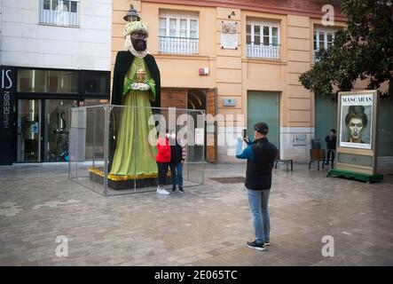 Malaga, Spanien. Dezember 2020. Menschen mit Gesichtsmasken machen ein Foto vor einer riesigen Figur, die Balthazar, einen der drei Weisen, in der Compania Street darstellt.das Rathaus von Málaga hat in Straßen und Plätzen riesige Figuren der drei Weisen platziert, die Kinder und Familien zum Genießen und Besuchen bringen, Ein paar Tage vor der Epiphanie Parade der drei Könige. Die Zahlen messen 5 Meter und sind mit Schutzschirmen isoliert, um die Coronavirus-Krankheit zu verhindern. Kredit: SOPA Images Limited/Alamy Live Nachrichten Stockfoto