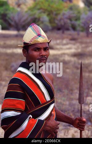 Porträt des Tribal Antrandroy Krieger oder Stammesmann tragen traditionelle Malagasy Lamba, Strohhut & Tragen eines Speers in Süd-Madagaskar Stockfoto