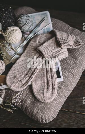Ein Paar handgestrickte Socken mit Garnkugeln. Natürliche Farben. Dunkler rustikaler Holzhintergrund. Stockfoto