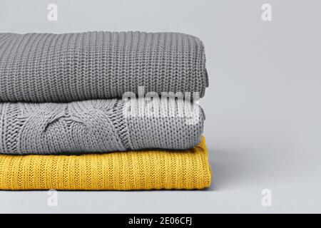 Stapel von gefalteten warmen Strickpullover für Damen in den Farben Gelb und Grau von 2021 Jahr. Speicherplatz kopieren. Stockfoto