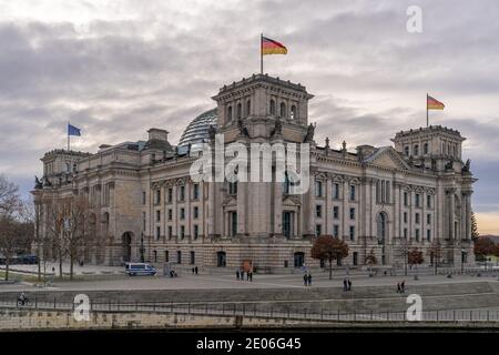 28. Dezember 2020, Berlin, das Reichstagsgebäude von Baumeister Paul Wallot auf dem Platz der Republik mit Fahnen am Tag bei bewölktem Himmel. Der Reichstag ist Sitz des Deutschen Bundestages mit Plenarsaal. Seitenansicht von der Spree-Seite. Weltweite Nutzung Stockfoto