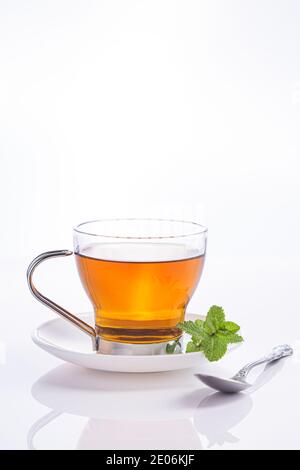 Infusion von Pfefferminze in Kristallglas und frischen Minzblättern, isoliert auf weißem Hintergrund. Stockfoto