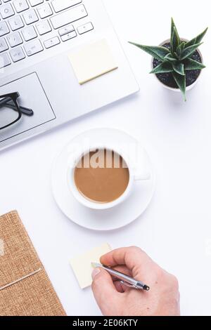 Flaches Lay, Arbeitsplatz mit Laptop, Kaffee und Notizen auf dem Schreibtisch. Vertikales Format, Draufsicht. Stockfoto