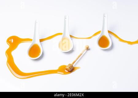 Weiße Löffel und Honigstock, mit verschüttetem Honig isoliert auf weißem Hintergrund Stockfoto