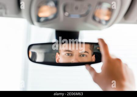 Beschnittene Ansicht des Mannes, der den Rückspiegel im Fahrzeug anpasst Verschwommener Vordergrund Stockfoto