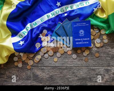 Brasilianische Arbeitskarte auf Holztisch mit brasilianischer Flagge und Münzen Stockfoto