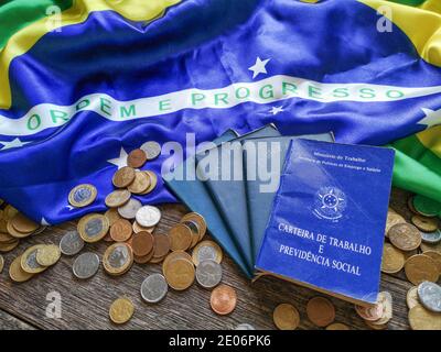 Brasilianische Arbeitskarte auf Holztisch mit brasilianischer Flagge und Münzen Stockfoto