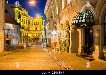 Nachtansicht der beleuchteten Ausros Vartu Straße in der Altstadt von Vilnius, Litauen. Das Royale Hotel befindet sich auf der rechten Seite. Litauische Nationale Philharmonische Gesellschaft Stockfoto