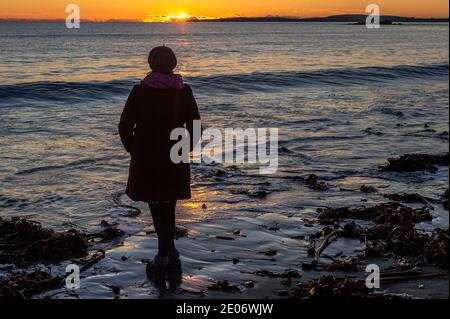 Garrylucas, West Cork, Irland. Dezember 2020. Am Garrylucas Beach in West Cork laufen die Menschen entlang, wenn die Sonne nach einem Tag Wintersonnenbaden untergeht. Das Land wird voraussichtlich aufgrund der Spirale der COVID-19-Fälle in eine Stufe-5-Sperre fallen. Quelle: AG News/Alamy Live News Stockfoto