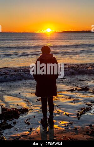 Garrylucas, West Cork, Irland. Dezember 2020. Am Garrylucas Beach in West Cork laufen die Menschen entlang, wenn die Sonne nach einem Tag Wintersonnenbaden untergeht. Das Land wird voraussichtlich aufgrund der Spirale der COVID-19-Fälle in eine Stufe-5-Sperre fallen. Quelle: AG News/Alamy Live News Stockfoto