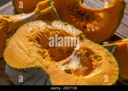 Nahaufnahme und Draufsicht auf einen frisch geschnittenen Kürbis auf einem Holztisch unter Sonnenlicht. Verwischen Sie den Hintergrund, während der Fokus auf dem Schnittbereich liegt. Food-Foto Stockfoto