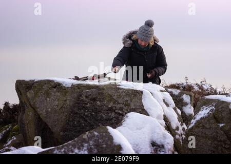 Junge Künstlerin Malerei, en plein air, eine Landschaft im Freien im Schnee auf Ilkley Moor an einem winterlichen Tag, West Yorkshire, England, Großbritannien Stockfoto