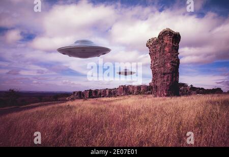 Zwei UFOs fliegen über uralte Felsen. Nicht identifizierte fliegende Objekte fliegen über den Himmel. 3D-Illustration mit Clipping-Maske im Lieferumfang enthalten. Stockfoto