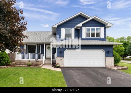 Außenansicht eines Vorstadthauses mit blauem Abstellgleis, einer weißen Veranda und weißen Fensterläden. Stockfoto