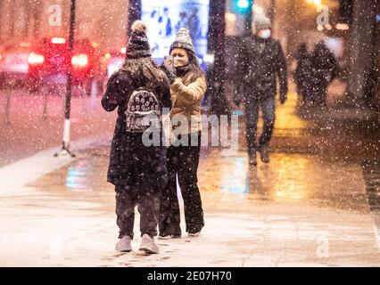 Chicago, USA. Dezember 2020. Eine Frau filmt ihre Freundin während eines Wintersturms in der Innenstadt von Chicago, USA, am 29. Dezember 2020. Morgen Pendler in Chicago erlebt eisige Straßen und langsamen Verkehr am Mittwoch als der erste große Wintersturm traf die Stadt. Der Schnee begann Chicago am Dienstagnachmittag zu bedecken und endete am frühen Mittwoch, mit anhaltendem Nieselregen bis 10 Uhr mittags. Quelle: Joel Lerner/Xinhua/Alamy Live News Stockfoto