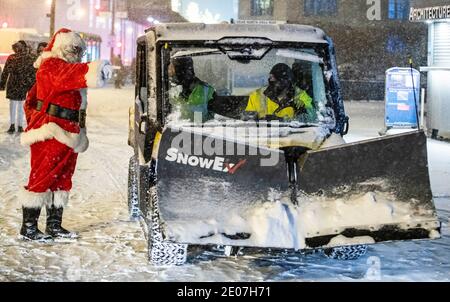 Chicago, USA. Dezember 2020. Ein Bürgersteig pflügenden Crew begrüßen einen Mann als Weihnachtsmann gekleidet während eines Wintersturms in der Innenstadt von Chicago, die Vereinigten Staaten, am 29. Dezember 2020. Morgen Pendler in Chicago erlebt eisige Straßen und langsamen Verkehr am Mittwoch als der erste große Wintersturm traf die Stadt. Der Schnee begann Chicago am Dienstagnachmittag zu bedecken und endete am frühen Mittwoch, mit anhaltendem Nieselregen bis 10 Uhr mittags. Quelle: Joel Lerner/Xinhua/Alamy Live News Stockfoto