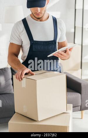 mover in einheitliche halten digitale Tablette und Blick auf Box In der Wohnung Stockfoto